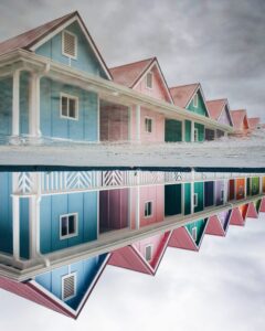 Painted terraced houses in blues, pinks and greens and reflected in water